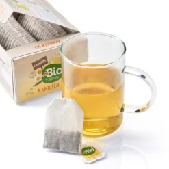 dmBio Organic Chamomile Tea – glass cup of golden tea with a tea bag and open box